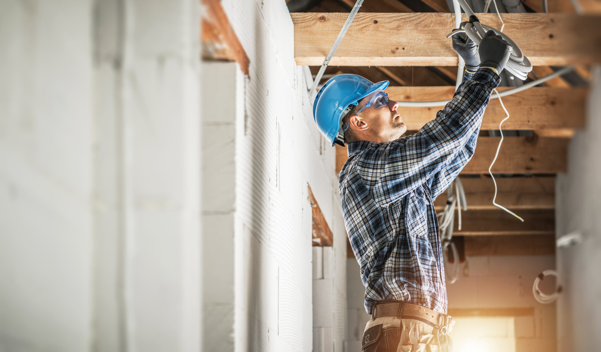 Professional Caucasian Electrician Working on Electrical Wiring System Installation in New Residential House Ceiling.