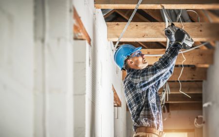 Professional Caucasian Electrician Working on Electrical Wiring System Installation in New Residential House Ceiling.